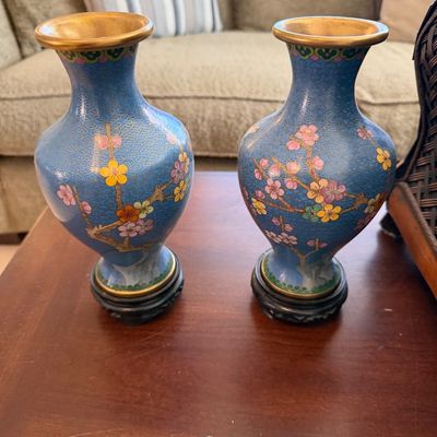 Pair of vintage blue cloisonné miniature vases featuring floral cherry blossom motifs on dark carved wooden stands.