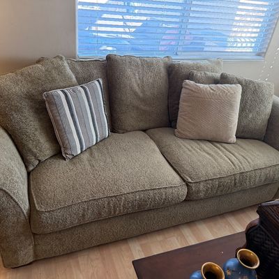 Contemporary textured sage green upholstered sofa with rolled arms, plush back cushions, and coordinating throw pillows.