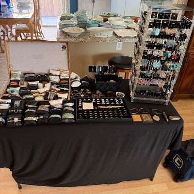 Tabletop display featuring a large selection of costume jewelry, including cased watches and bracelets, a ring display tray, and a...
