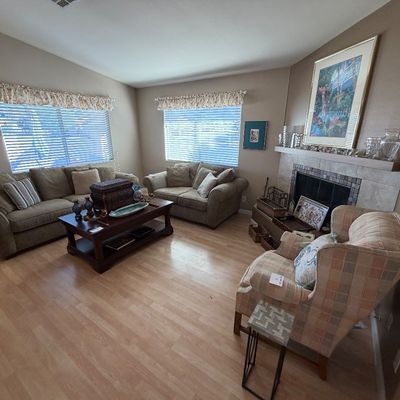 Living room set including a light green upholstered sofa and matching loveseat, dark wood coffee table, and a plaid wingback armchair.