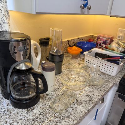 Collection of small kitchen appliances and glassware, including a Mr. Coffee drip coffee maker, Ninja single-serve blender, electric...