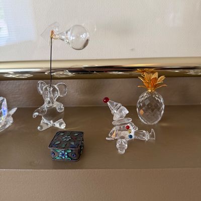 Collection of crystal and glass miniatures, including a Swarovski clown, a pineapple figurine with gold metal top, a bear holding a...