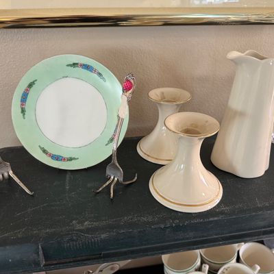 Collection of tabletop decor including two bent-fork card or photo holders, a hand-painted floral saucer, cream ceramic candlesticks, and...