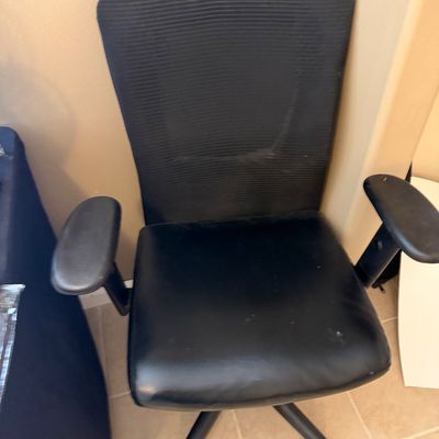 Contemporary black mesh office chair featuring an upholstered seat cushion, adjustable armrests, and a five-star wheeled base.