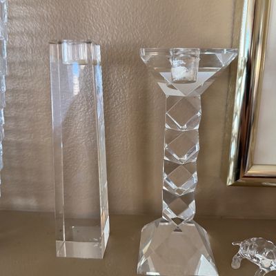 Two clear crystal candlesticks including a geometric faceted column candlestick and a tall rectangular prism candlestick.