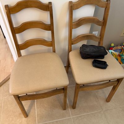 Pair of ladderback dining chairs with light-colored padded seats and a natural wood finish.