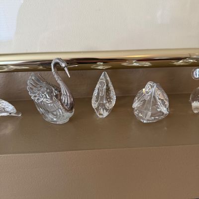 Collection of small crystal and glass swan figurines, including a metal-headed swan salt cellar and Swarovski-style faceted crystal swans.