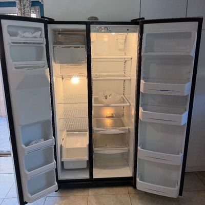Side-by-side refrigerator and freezer unit shown open with interior lighting on.