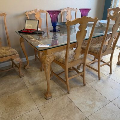 Traditional glass-top dining table with carved cabriole legs, paired with six matching high-back dining chairs with upholstered seats.