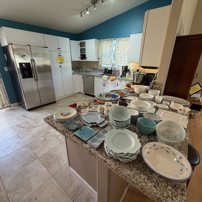 A kitchen counter filled with an assortment of ceramic dishes, bowls, and serving pieces, set against a backdrop of modern appliances.