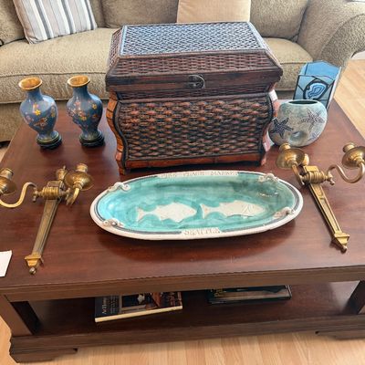 Selection of decorative home items displayed on an Aspen Home wooden coffee table, including a woven trunk box, pair of brass wall...