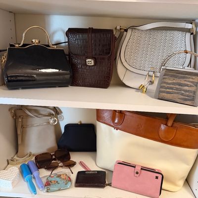 Shelves displayed with a collection of women's handbags, wallets, sunglasses, and personal accessories in various styles and materials.