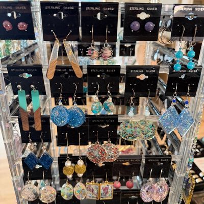 Rotating clear acrylic jewelry display stand filled with assorted contemporary sterling silver dangle and stud earrings, featuring resin,...