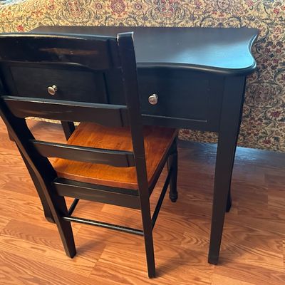 Sale Photo Thumbnail #69: Black painted wooden writing desk with two drawers and silver-tone knobs, paired with a matching ladder-back chair featuring a natural wood seat.