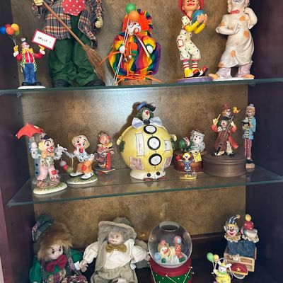 Sale Photo Thumbnail #12: Collection of vintage clown figurines, dolls, and a snow globe displayed inside a wooden curio cabinet.