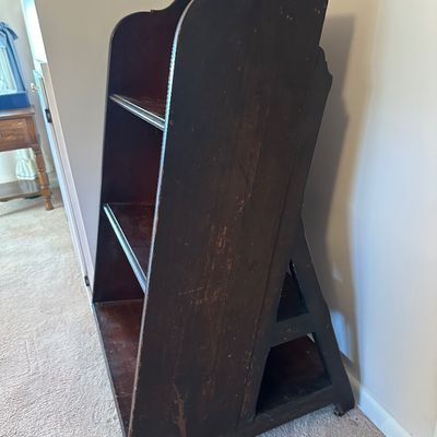 Sale Photo Thumbnail #151: Vintage dark-stained wooden bookshelf featuring scalloped side panels and three tiered shelves, showing moderate surface wear and finish distressing.