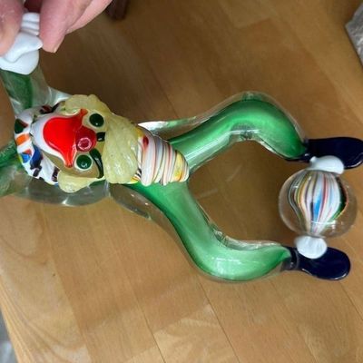 Sale Photo Thumbnail #3: Vintage Murano-style blown glass clown figurine balancing a striped ball on its feet, featuring a green body and colorful accents.