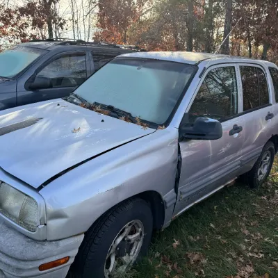 Sale Photo Thumbnail #161: Silver Chevy Tracker compact SUV with minor body wear, parked outdoors next to another vehicle.