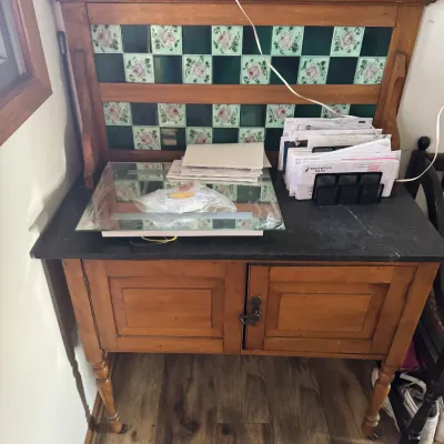 Sale Photo Thumbnail #49: Antique wooden washstand featuring a tiled splashback with green and floral designs, a dark top, and a two-door lower cabinet.