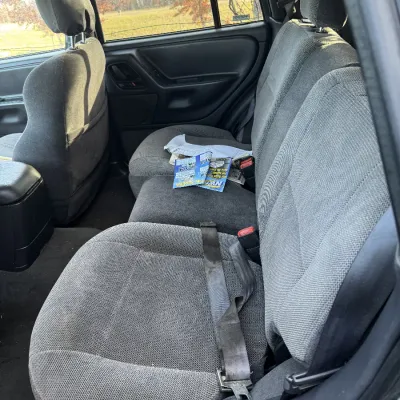 Sale Photo Thumbnail #149: Interior view of a vehicle's rear bench seat with grey cloth upholstery in well-maintained condition.