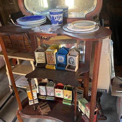 Sale Photo Thumbnail #192: Antique wooden display shelf featuring an oval mirror top, populated with decorative ceramics and a collection of vintage tin match safe holders.