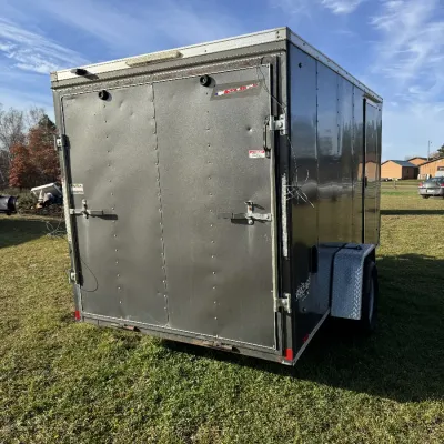 Sale Photo Thumbnail #132: Single-axle enclosed cargo trailer featuring dual rear barn doors with bar locks, side door access, and diamond-plate fenders.