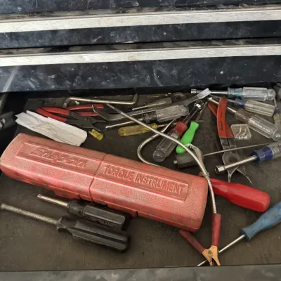 Sale Photo Thumbnail #80: Toolbox drawer filled with assorted hand tools, including screwdrivers, pliers, and a red Snap-on torque instrument case.