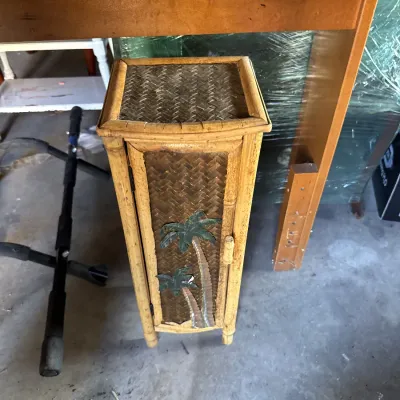 Sale Photo Thumbnail #107: Vintage wicker and bamboo pedestal cabinet featuring woven panels and applied palm tree accents on the front door.