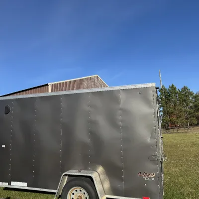Sale Photo Thumbnail #131: Pace American OutBack DLX single-axle enclosed cargo trailer in dark gray, featuring diamond plate fenders and side door.