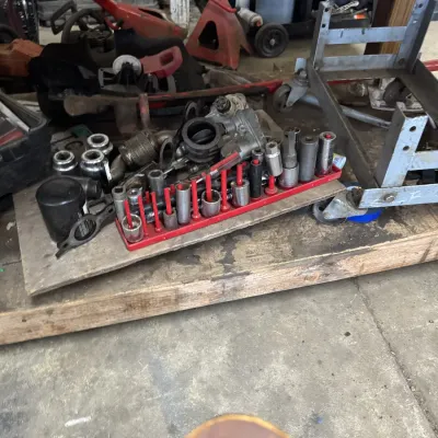 Sale Photo Thumbnail #61: Assorted socket set on a red organizer rack alongside automotive parts, a floor jack, and shop equipment.