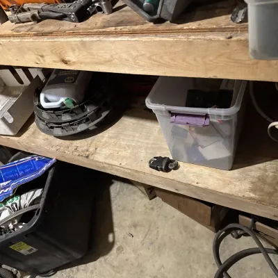 Sale Photo Thumbnail #56: Wooden workshop shelving unit stored with various automotive supplies, plastic storage totes, hubcaps, tools, and hardware.