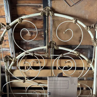Sale Photo Thumbnail #106: Vintage off-white iron bed frame featuring intricate scrollwork and ornate brass accents, showing light wear.
