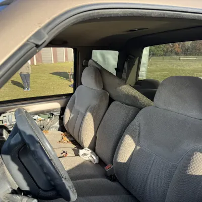 Sale Photo Thumbnail #163: Interior view of a pickup truck featuring tan cloth seats and a missing driver's side door panel.