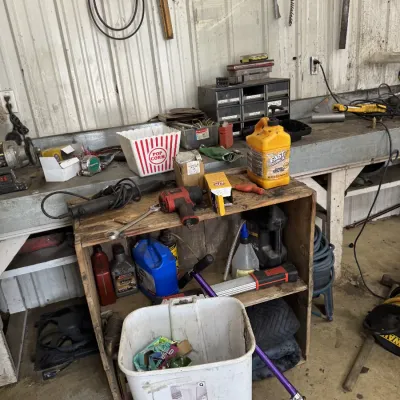 Sale Photo Thumbnail #65: Workshop shelf and bench loaded with assorted hand tools, power tools, automotive fluids, and garage supplies.