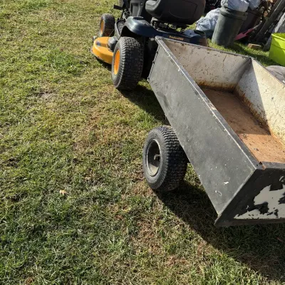 Sale Photo Thumbnail #118: Poulan Pro riding lawn mower attached to a heavy-duty tow-behind dump cart, showing moderate wear and rust.