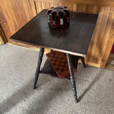 Sale Photo Thumbnail #12: Dark stained wooden accent table with spindle legs, holding a carousel poker chip set on top and a folded wooden chessboard on the lower shelf.