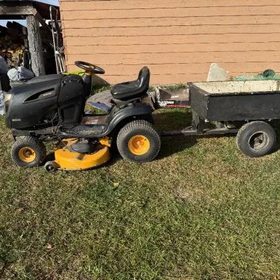 Sale Photo Thumbnail #126: Poulan Pro black and yellow riding lawn mower paired with a tow-behind utility cart.
