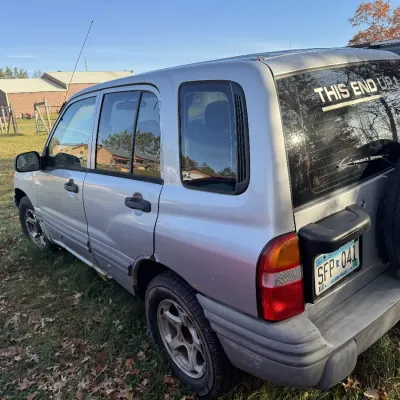 Sale Photo Thumbnail #158: Silver late-1990s to early-2000s Chevrolet Tracker SUV with a rear spare tire and Minnesota license plates.