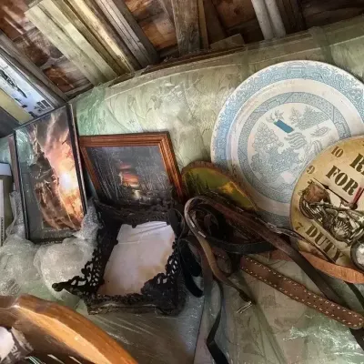 Sale Photo Thumbnail #114: Assortment of household goods including a novelty motorcycle wall clock, Blue Willow style platter, leather belts, framed artwork, and a vintage canister vacuum cleaner.