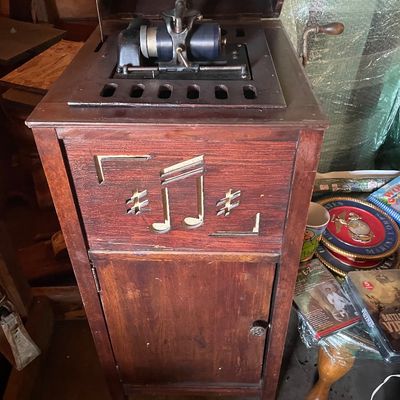Sale Photo Thumbnail #188: Antique Edison cylinder phonograph housed in a wooden floor-standing cabinet with carved musical note cutouts and hand crank, early 20th century.