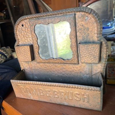 Sale Photo Thumbnail #190: Antique embossed tin wall-hanging match box and comb-and-brush holder featuring a central mirror and two side match slots.