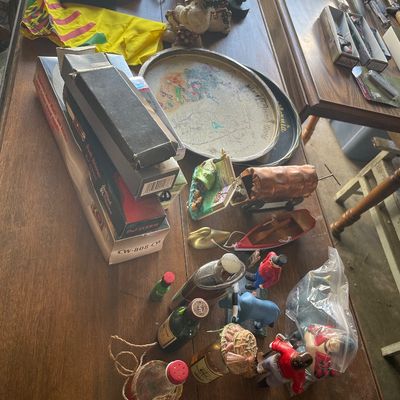 Sale Photo Thumbnail #200: Collection of assorted vintage collectibles including miniature liquor bottles, small figurines, a souvenir metal tray, and boxed items displayed on a wooden dining table.