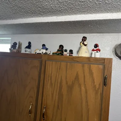 Sale Photo Thumbnail #16: Collection of vintage Black Americana figurines and novelty items displayed on top of a wooden cabinet.