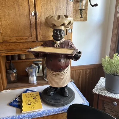 Sale Photo Thumbnail #36: Vintage painted chef waiter statue with a serving tray, displayed on a kitchen counter near oak cabinetry.