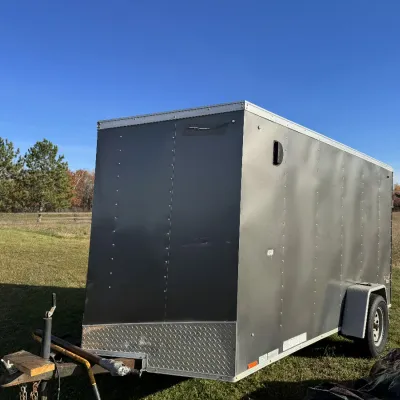 Sale Photo Thumbnail #136: Enclosed single-axle cargo trailer featuring silver metal siding, diamond plate trim, and a v-nose design.