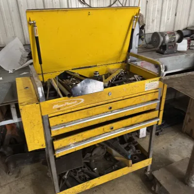 Sale Photo Thumbnail #67: Yellow Blue-Point rolling tool cart with a flip-top lid, multiple drawers, and bottom shelf, showing wear and filled with various tools.