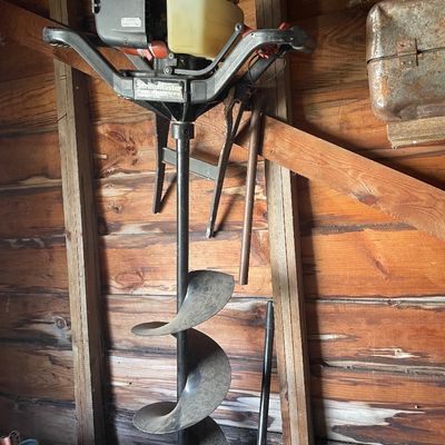 Sale Photo Thumbnail #206: StrikeMaster gas-powered ice auger stored in a wooden shed. Shows typical wear from use and age.