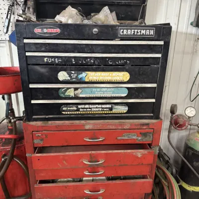 Sale Photo Thumbnail #71: Craftsman black metal top tool chest sitting on a red Dayton rolling tool cabinet, showing signs of heavy workshop use.
