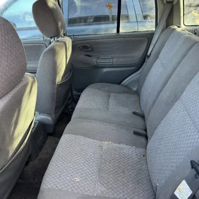 Sale Photo Thumbnail #155: Interior rear bench seating of a late 1990s or early 2000s SUV with gray cloth upholstery, showing light wear and debris.