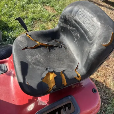 Sale Photo Thumbnail #140: Craftsman riding lawn mower seat featuring significant vinyl tearing and exposed inner foam.